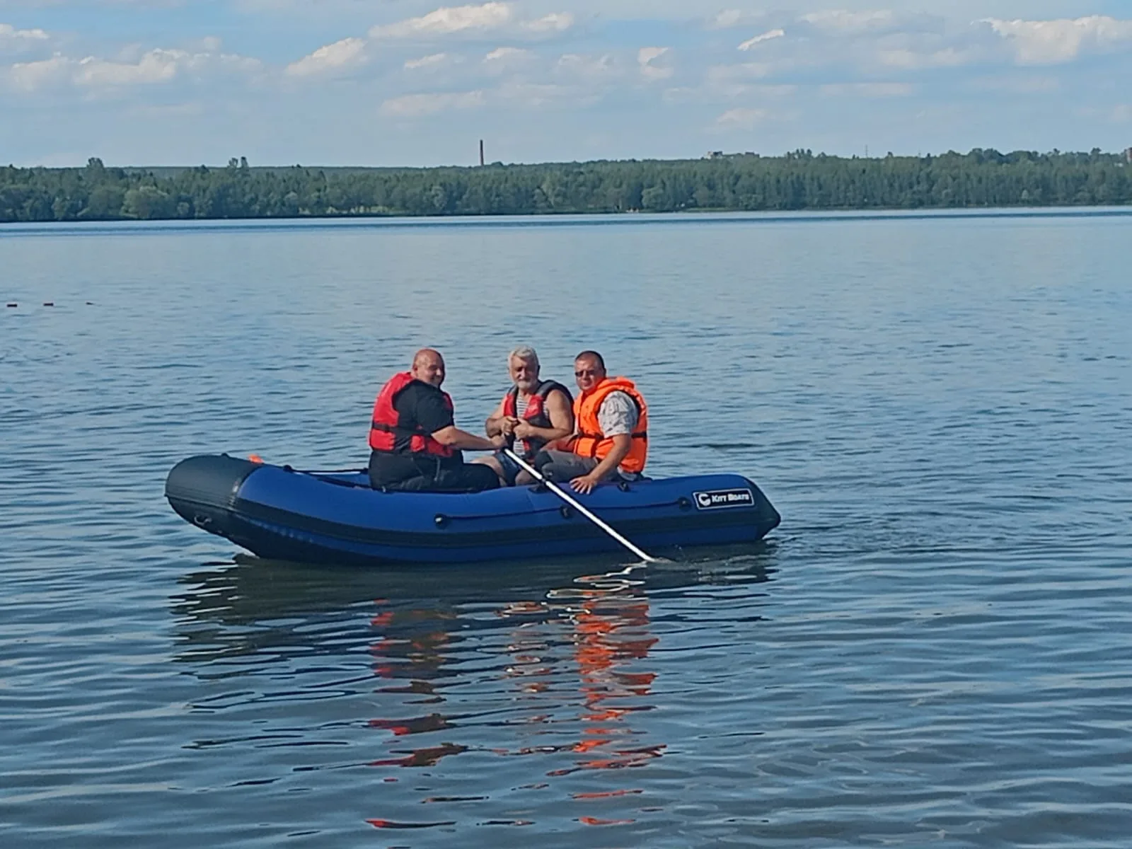 Компания в спасательных жилетах плывёт на синей лодке KITT BOATS
